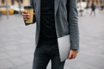 Körper von Mann in Anzug mit Kaffebecher und Laptop in der Hand